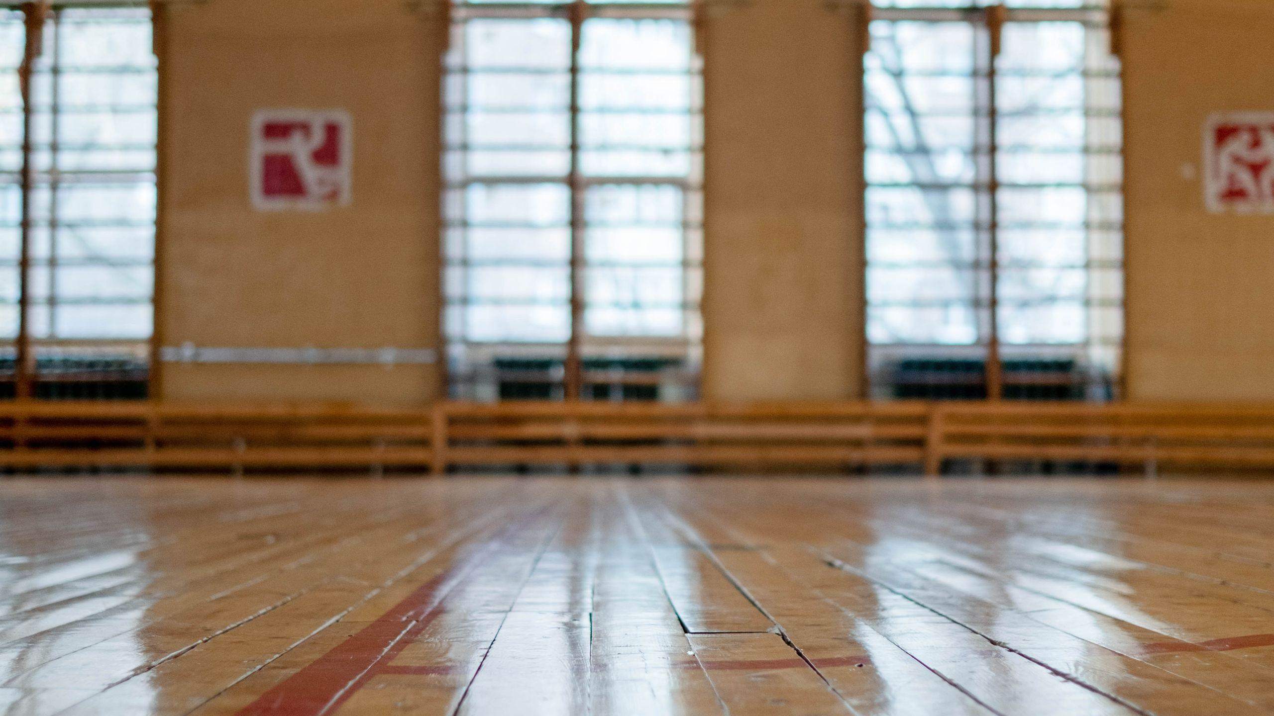 A sunlit sports hall with a polished wooden floor